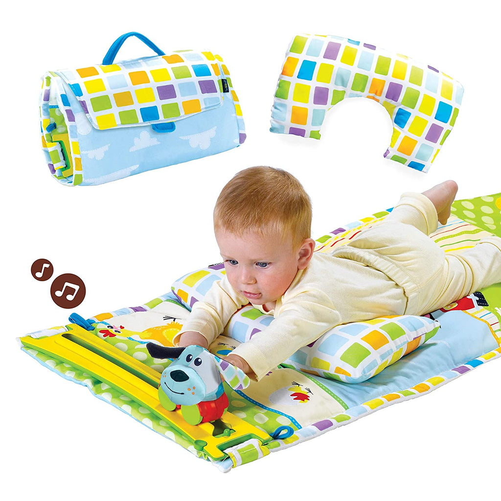 A baby lying on a colorful tummy time playmat with plush farm figures and a large pillow, with the mat shown rolled up and another section unfolded.